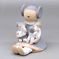 A sitting grandmother storyteller figure with three children and a bunny on her
 by Stella Teller of Isleta