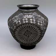 Black on black jar with flared lip, indented body, medallion and geometric design
 by Eduardo Ortiz aka Chevo of Mata Ortiz and Casas Grandes