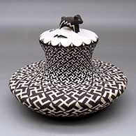 A lidded black on white low shouldered jar with a recurved neck and decorated with a spiraling whirling logs and geometric design
 by Barbara and Joseph Cerno Sr of Acoma