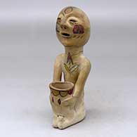 A polychrome Rain God holding a pot in his lap
 by Unknown of Tesuque