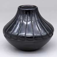 A small black jar decorated with a carved ring of feathers design above the shoulder
 by Denise Chavarria of Santa Clara