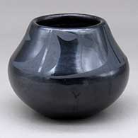 A black on black jar decorated with a four panel geometric design above the shoulder
 by Maria Martinez of San Ildefonso