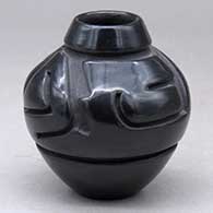 A small black jar carved with a stylized avanyu design around the shoulder
 by Denise Chavarria of Santa Clara