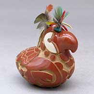A red and golden micaceous parrot figure decorated with a carved and painted bird element design, plus feathers on the head
 by Autumn Borts of Santa Clara
