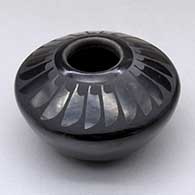 A small black on black jar decorated with a ring of feathers design above the shoulder
 by Adam and Santana Martinez of San Ildefonso