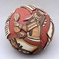 A polychrome seed pot decorated with a carved and painted pueblo dancers and geometric design
 by Thomas Polacca of Hopi