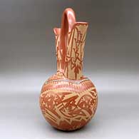 A large red wedding vase decorated with a sgraffito double avanyu, feather,bear paw and geometric design with inlaid stones and strands of heishi beads, click or tap to see a larger version