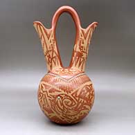 A large red wedding vase decorated with a sgraffito double avanyu, feather,bear paw and geometric design with inlaid stones and strands of heishi beads, click or tap to see a larger version