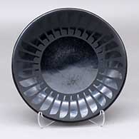 A black-on-black plate decorated with a ring of feathers design
 by Maria Martinez of San Ildefonso