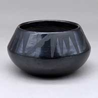 A black on black bowl decorated with a four panel geometric design above the shoulder
 by Maria Martinez of San Ildefonso