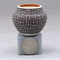 A miniature polychrome jar decorated with a geometric design built of tiny squares filled in
 by Frederica Antonio of Acoma