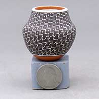 A miniature polychrome jar decorated with a geometric design built of tiny squares
 by Frederica Antonio of Acoma