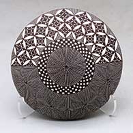 A black on white seed pot decorated with a North Star fineline, yucca leaf snowflake, checkerboard and geometric design above the shoulder
 by Rebecca Lucario of Acoma