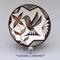 A small polychrome plate decorated with a hummingbird, flower and geometric design
 by Carolyn Concho of Acoma