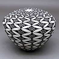 A black on white seed pot decorated with a pumpkin seed snowflake and geometric design
 by Cletus Victorino of Acoma