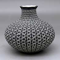 A black on white jar with a short neck and pie crust rim decorated from top to bottom with a swirling geometric design
 by Paula Estevan of Acoma