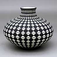 A black on white jar with a short neck decorated from top to bottom with a spiral checkerboard design
 by Paula Estevan of Acoma