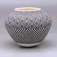 A black on white jar decorated with a checkerboard design below the shoulder and with a tiny square geometric design above the shoulder
 by Frederica Antonio of Acoma