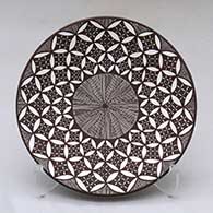 A black on white plate decorated with a fineline, yucca leaf snowflake and geometric design
 by Amanda Lucario of Acoma