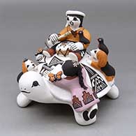 A polychrome turtle figure with thee children, puppies, birds, lady bugs and butterflies
 by Marilyn Ray of Acoma