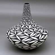 A black on white vase with a tall, thin neck and decorated with a yucca leaf snowflake and geometric design
 by Sandra Victorino of Acoma