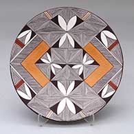 A polychrome plate decorated with a pumpkin seed, fineline and geometric design
 by Shaylene Chino of Acoma