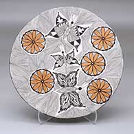 A polychrome plate decorated with a butterfly, flower and fineline geometric design with two butterfly appliques on the back
 by Alisha Sanchez of Acoma