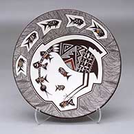 A polychrome plate decorated with a cloudeater, fish and fineline geometric design with a fish applique on the back
 by Carolyn Concho of Acoma