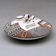 A polychrome seed pot decorated above the shoulder with  dog, dog bone and water bowl appliques and a fineline and geometric design
 by George Concho Jr of Acoma