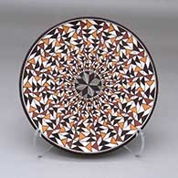 A polychrome plate decorated with a fineline flower design in the center surrounded by a geometric design
 by Sharon Lewis of Acoma
