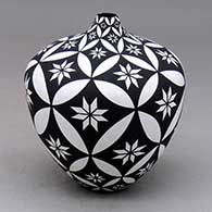 A black on white tear drop jar decorated with a pumpkin seed snowflake, flower and geometric design
 by Dorothy Torivio of Acoma