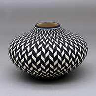 A black on white jar decorated with a basket weave geometric design
 by Paula Estevan of Acoma