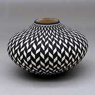 A black on white jar decorated with a basket weave geometric design
 by Paula Estevan of Acoma