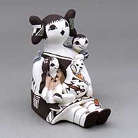 A sitting grandmother storyteller with two children, a cat, bird, butterfly, lady bug and pot
 by Judy Lewis of Acoma