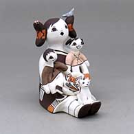 A sitting grandmother storyteller with two children, a cat, bird, butterfly, lady bug and pot
 by Judy Lewis of Acoma