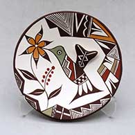 A small polychrome plate decorated with hummingbird wing and lady bug appliques and a painted hummingbird, flower, lady bug, fineline and geometric design
 by Carolyn Concho of Acoma