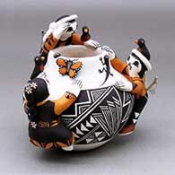 Three children clinging to the outside of a black on white jar with geometric design, plus painted bird, lady bug, lizard and butterfly appliques, and tiny slingshots
 by Marilyn Ray of Acoma