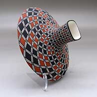 A polychrome low shouldered jar with a squarish neck and rim and decorated with a spiral checkerboard and geometric design, click or tap to see a larger version