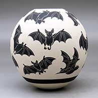 A black on white jar decorated with a lightly carved and sgraffito flying bat design, click or tap to see a larger version
