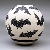 A black on white jar decorated with a lightly carved and sgraffito flying bat design, click or tap to see a larger version
