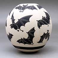 A black on white jar decorated with a lightly carved and sgraffito flying bat design, click or tap to see a larger version