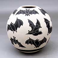 A black on white jar decorated with a lightly carved and sgraffito flying bat design
 by Adrian Corona of Mata Ortiz and Casas Grandes