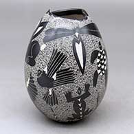 A black on white jar with a geometric cut opening and decorated with a sgraffito wildlife and geometric design
 by Alex Ortega of Mata Ortiz and Casas Grandes