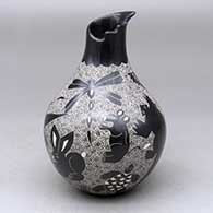 A black on white jar with a geometric cut opening on a short neck and decorated with a sgraffito wildlife and geometric design
 by Alex Ortega of Mata Ortiz and Casas Grandes