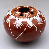A white on red jar decorated with a five-panel geometric design matching a five-directional geometric cut opening in the top
 by Avelina Corona of Mata Ortiz and Casas Grandes