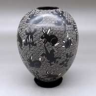 A black on white jar decorated with a sgraffito wildlife and mesh design
 by Alex Ortega of Mata Ortiz and Casas Grandes