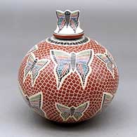 A polychrome jar decorated with a sgraffito and painted butterfly, mesh and geometric design, with a butterfly on the lid
 by Oscar Ramirez of Mata Ortiz and Casas Grandes