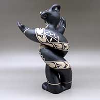 A polychrome mudhead figure all twisted up and holding his arms out, and decorated with a geometric design, click or tap to see a larger version