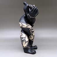 A polychrome mudhead figure all twisted up and holding his arms out, and decorated with a geometric design, click or tap to see a larger version
