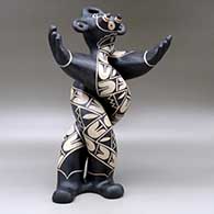 A polychrome mudhead figure all twisted up and holding his arms out, and decorated with a geometric design, click or tap to see a larger version